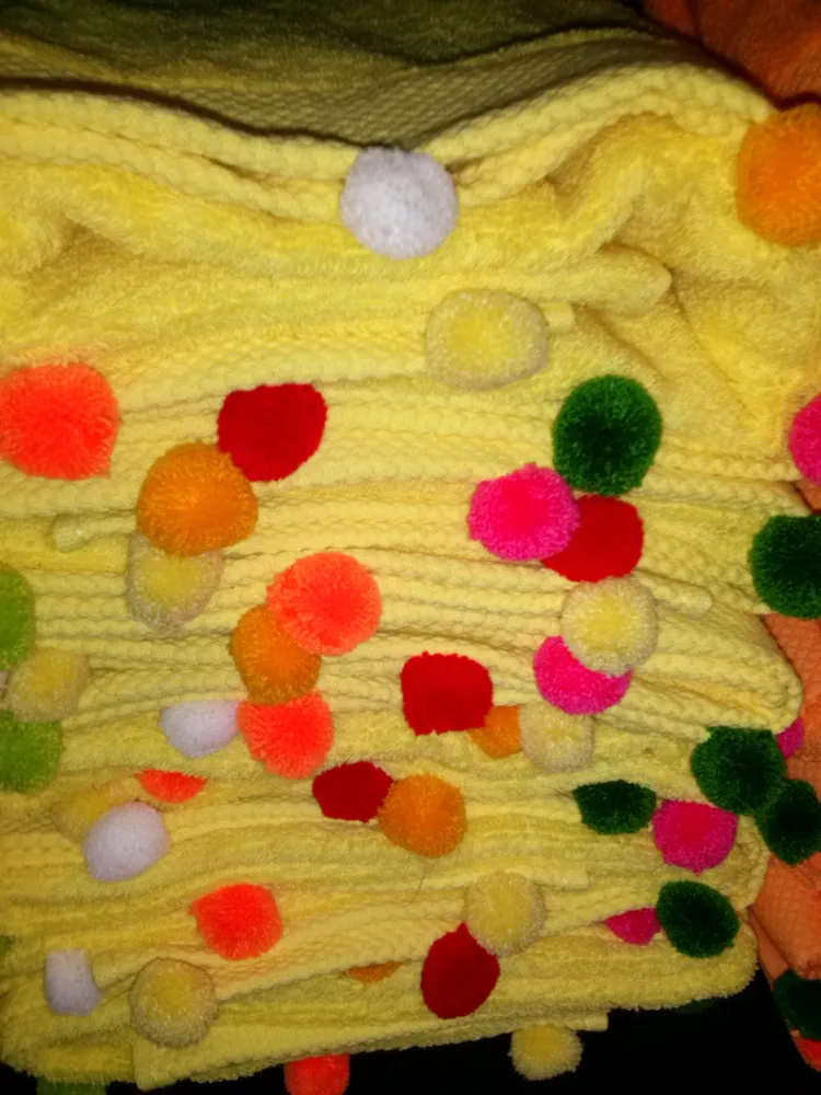 Zdjęcie prezentuje kilka ręczników złożonych gdzie widać małe kolorowe pompony.